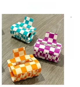 Detail of square checkered PVC hair claws in green, purple and orange on wooden background