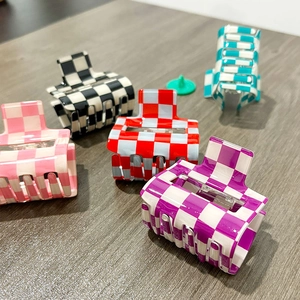 Five assorted checkerboard PVC hair claw clips in vibrant colors on a wooden surface