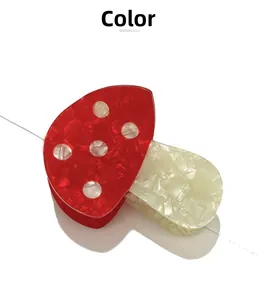 Détail de la pince à cheveux champignon rouge à pois blancs en matériau acétate fini