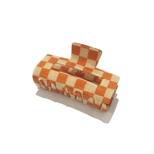 Detailed view of the square orange and beige checkered pattern claw clip with glossy finish