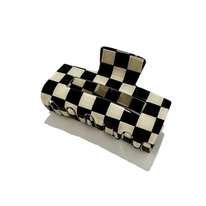 Close-up of black and white checkerboard hair claw clip with glossy finish