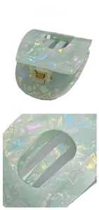 Detail view of the pale green acetate hair claw with shell texture and golden metal spring