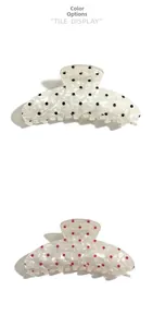 Detail view of large shell-textured hair claws with black and red polka dots pattern