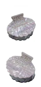 Macro shot of seashell hair claw with pink pearl finish and sparkling rhinestone inlay