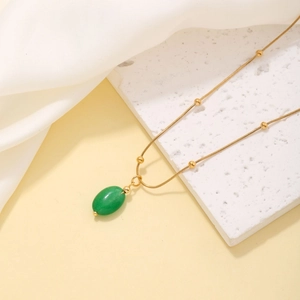 Elegant gold drop necklace with green oval pendant on a snake chain and white stone base