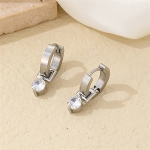 Detailed view of silver hoop earrings with round cubic zirconia on a stone surface