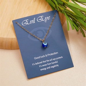 Dettaglio della collana Evil Eye blu su catena dorata con carta su sfondo in legno