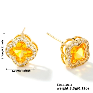 Détail de boucles d'oreilles trèfle doré avec pierres jaunes et cristaux blancs