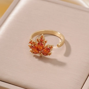 Bague ajustable feuille d'érable dorée avec pierres orange sur un écrin de luxe en satin