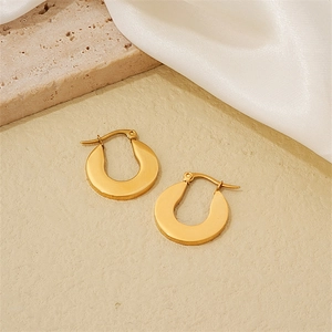 Minimalist brushed gold horseshoe earrings on a stylish travertine and silk display