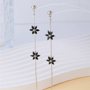 Detail of silver tassel earrings with double black flower elements on white display