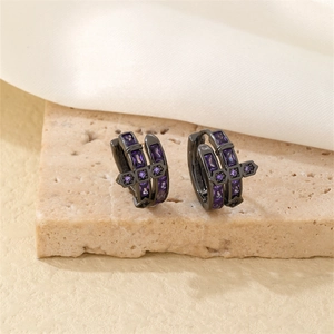 Détail de créoles noires avec breloques croix en zircon violet sur socle en pierre texturé
