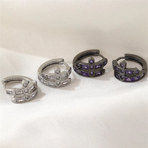 Détail de boucles d'oreilles hip-hop avec zircons rectangulaires et motif de croix gravé