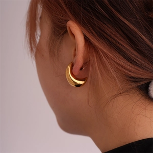 Close-up of golden crescent hoop earrings on model showing glossy mirror finish