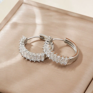 Elegant silver-toned baguette-cut cubic zirconia hoop earrings on champagne satin