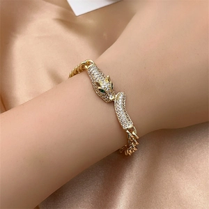 Close-up of gold leopard head bracelet with green gemstone eyes and pavé stones