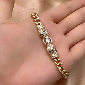 Macro detail of gold-plated cuban chain bracelet featuring dual leopard heads with white zircons