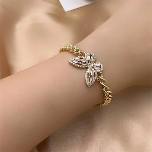 Detail of a gold-plated Cuban chain bracelet with a butterfly charm set with zircons