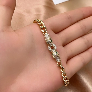 Macro detail of gold-plated cuban bracelet featuring dual leopard heads with pave zircons