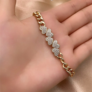 Detail of gold-plated Cuban chain bracelet with heart charms and micro-inlaid zircons