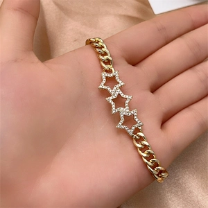 Detail of gold-plated Cuban link bracelet with sparkling star charms in close-up hand shot