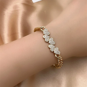 Detail view of gold heart charm bracelet with paved zircons on silk fabric