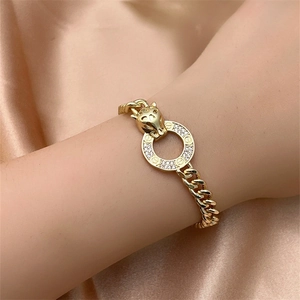 Detail view of a gold cheetah head bracelet with a sparkling crystal-set ring on a satin wrist