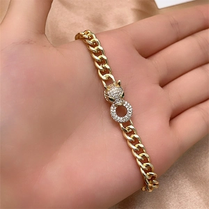 Close-up of golden leopard head bracelet with green gemstone eyes and Cuban link chain