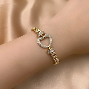 Detail of gold Cuban chain bracelet with a sparkling crystal-encrusted heart charm