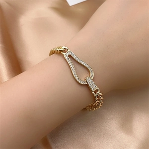 Close-up of gold Cuban chain bracelet featuring a horseshoe charm with white cubic zirconia