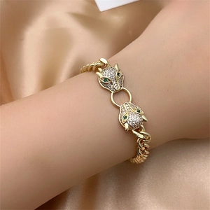 Detailed close-up of double leopard head gold bracelet with emerald eyes and zircon