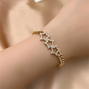 Detail of gold-plated star bracelet with white zircons on a champagne silk background