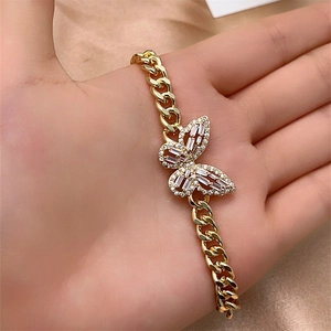 Detail of a gold-plated Cuban chain bracelet with a butterfly charm set in sparkling zircons