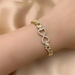 Detail of gold Cuban chain bracelet featuring crystal-paved interlocking infinity hearts
