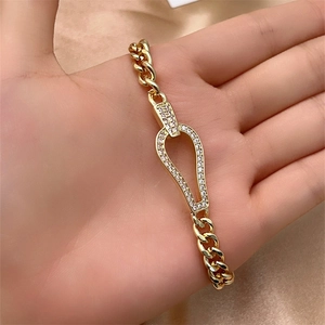 Close-up of gold Cuban link bracelet featuring a zircon-studded horseshoe buckle detail