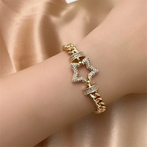Detail of gold Cuban chain bracelet with crystal-studded star on silk fabric background