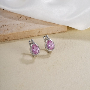 Détail macro de boucles d'oreilles zircon rose en forme de poire sur socle en pierre