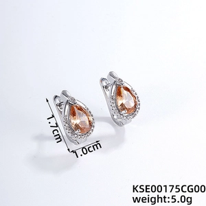 Détail de boucles d'oreilles argentées avec pierres orange et pavé de zircones clairs