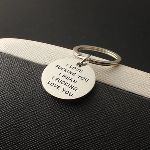 Detailed close-up of engraved stainless steel round keychain with romantic humor quote