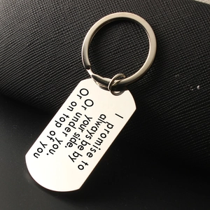 Polished stainless steel dog tag keychain with romantic quote on black leather background