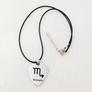 Scorpio guitar pick necklace in silver stainless steel with black wax cord on light background