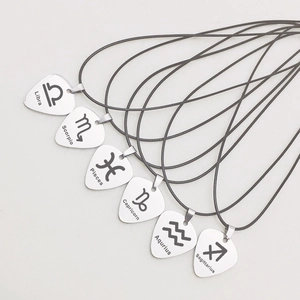 Close-up of polished stainless steel guitar pick pendants with zodiac signs on black cords