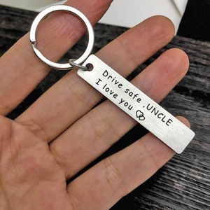 Close-up of Drive Safe Uncle stainless steel keychain with engraved text held by hand