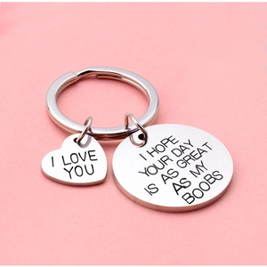 Polished stainless steel heart and round charm keychain with humorous quote on pink background