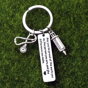 Medical nurse gift keychain with stethoscope and syringe charm on green moss background
