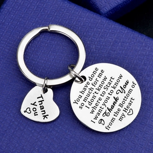 Stainless steel thank you keychain with engraved charms on a navy blue gift box