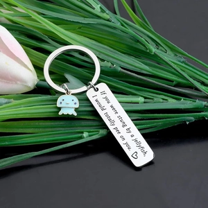 Funny jellyfish keychain with laser engraved tag and light blue enamel pendant on green plants