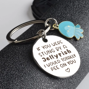 Detail view of round stainless steel keychain with blue enamel jellyfish and friendship quote