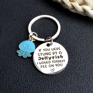 Detail of metal keychain with blue jellyfish charm and funny engraved round pendant