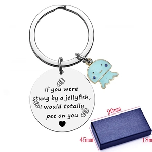 Macro detail of stainless steel keychain with jellyfish charm and engraved quote in gift box
